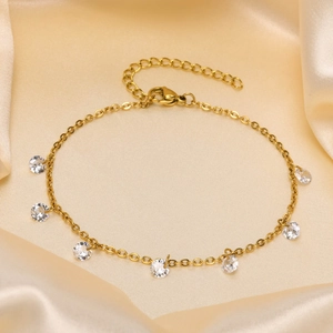 Detail of gold titanium steel anklet with clear zircons on premium silk background