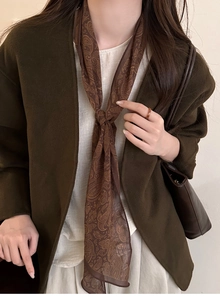 Detailed view of long brown paisley silk scarf necklace styled with winter wool coat