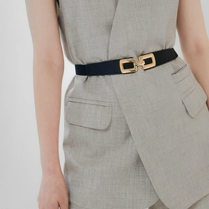 Close-up of black elastic dress belt featuring a gold rectangular interlocking metal buckle
