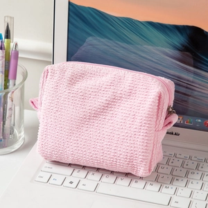 Macro detail of pink bubble textured makeup bag with zipper closure on laptop