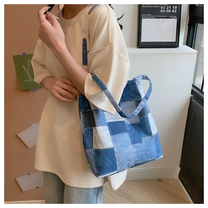 Detail of blue denim patchwork tote bag showing material texture and shoulder strap design
