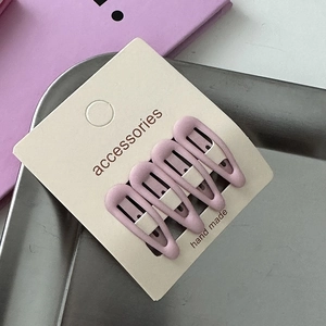 Detailed view of four matte purple teardrop hair clips on beige display card
