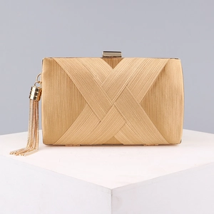 Close-up of golden evening clutch bag featuring vertical texture and elegant long tassels