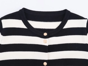 Detailed macro view of gold anchor buttons on a black and white striped knit cardigan