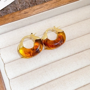 Detailed view of vintage amber tiger eye hoop earrings on a beige velvet jewelry box