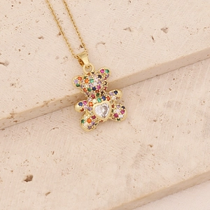 Detail of a gold teddy bear pendant with multi-color zircon stones on a stone surface