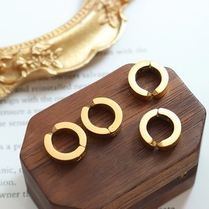 Set of four 18k gold plated stainless steel clip-on hoop earrings on a dark wood display