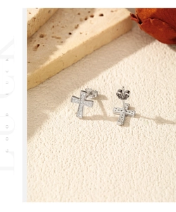 Macro shot of S925 silver cross stud earrings with pavé moissanite and butterfly backs