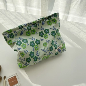 Détail de la pochette fleurie en toile vert clair avec marguerites et étiquette Suakka