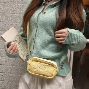 Detailed close-up of yellow crossbody bag featuring delicate white bow embroidery work