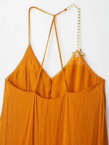 Détail de robe midi orange avec bretelles chaîne dorée et papillon en métal