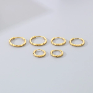 Set of six gold stainless steel hoop earrings in various sizes on a grey background