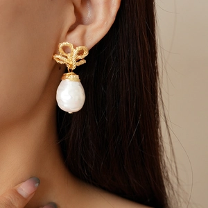 Detail of vintage flower metal knot earrings with baroque pearl drop on a model