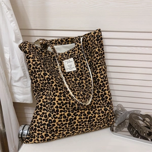 Detail of leopard print canvas tote bag featuring a decorative white square woven label