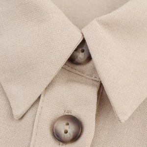 Detail of lapel collar with marble-textured buttons on khaki linen dress fabric