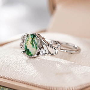 Macro detail of moss agate ring with silver heart hollow band and sparkling zircon accent