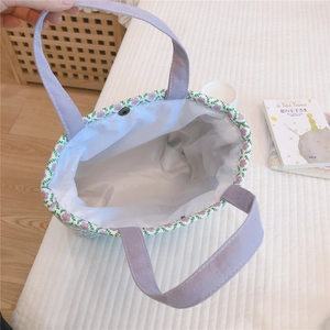 Close-up of floral lunch tote with purple straps, metal snap button, and white lining