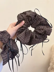 Close-up of brown plaid fabric scrunchie with long black ribbon detail for hair styling