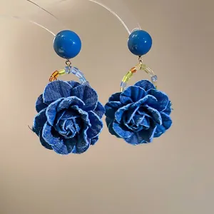 Élégantes boucles d'oreilles roses en denim bleu avec accents de perles colorées sur fond