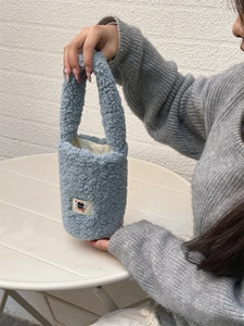 Detailed shot of a soft blue plush bottle carrier with a cute cat patch and handle