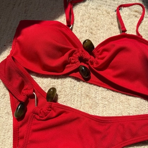 Detail of red ribbed bikini featuring textured fabric and decorative amber-tone oval beads