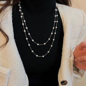 Détail d'un collier de perles double épaisseur porté par un mannequin au style vintage