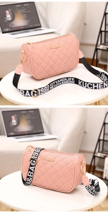 Detail of pink quilted crossbody bag featuring wide embroidered strap and gold hardware
