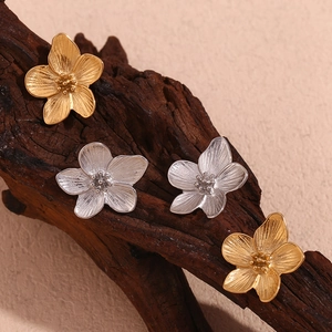 Minimalist 18K gold and silver stainless steel flower studs on textured wood