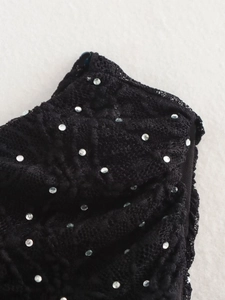 Gros plan sur un tissu en dentelle noire aux motifs complexes et strass argentés étincelants