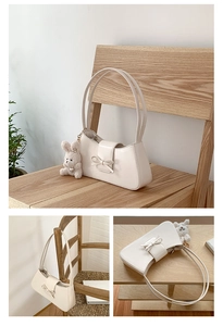White leather baguette bag with a bow decoration and a cute rabbit plush pendant detail