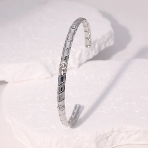 Detail of silver stainless steel cuff with diagonal texture and three clear crystals