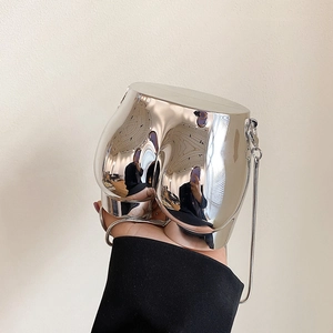 Fashionable mini silver metallic chain bag in unique shape held against light background