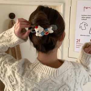Close-up of white plush bear hair clip with red hat on a braided hairstyle