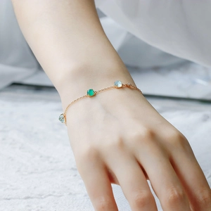Macro shot of 14k gold plated silver bracelet with green chalcedony and white shell on wrist