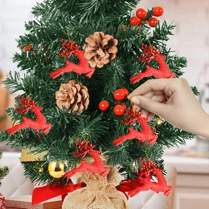 Sparkly red reindeer Christmas tree ornaments being hung on a festive pine tree branch