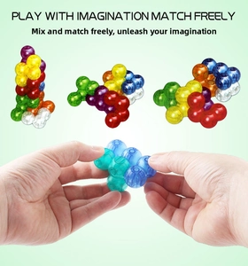 Macro view of hands assembling translucent magnetic cubes into 3D shapes for kids