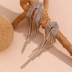 Detail of 18K gold plated tassel earrings with white zircons on a wooden branch