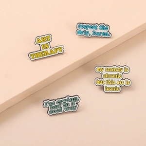 Détail de quatre épingles en émail colorées avec le texte Art is Therapy en couches