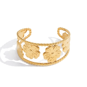 Macro detail of 18K gold stainless steel open bangle with embossed floral petal designs