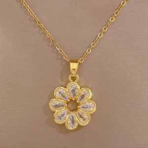 Close-up of gold flower pendant with clear crystals on a delicate cable chain