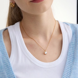 Nahaufnahme der 18k vergoldeten Edelstahl-Zirkonia-Halskette am Modell in blauer Strickjacke