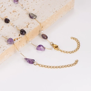 Fashionable gold necklace featuring irregular amethyst stones and pearls on stone base