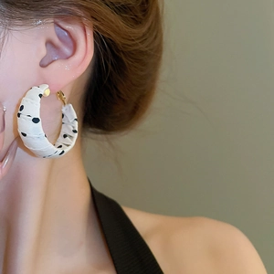 Close-up of polka dot fabric wrapped hoop earrings on a model showing detailed texture
