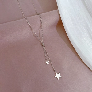 Macro detail of silver titanium steel Y-necklace featuring two star pendants on soft fabric