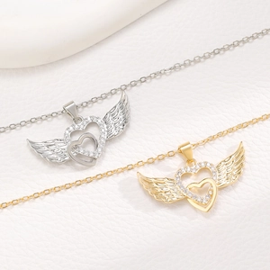 Detailed view of angel wing heart pendants in silver and gold with diamond inlay