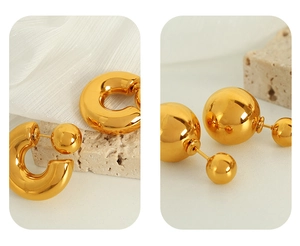 Detailed macro view of gold-plated hoop earrings with polished metallic sphere stoppers