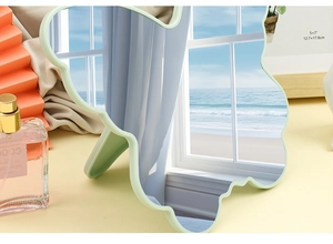 Detail of light green cloud-shaped vanity mirror with stand showing a clear ocean reflection