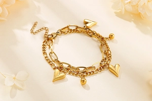 Detail of gold double-layer heart bracelet with spherical charms on a floral background