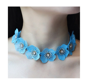 Dettaglio della collana a fiori in maglia blu con strass indossata da una modella