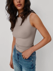 Vista laterale di una canotta taupe senza maniche slim fit abbinata a jeans